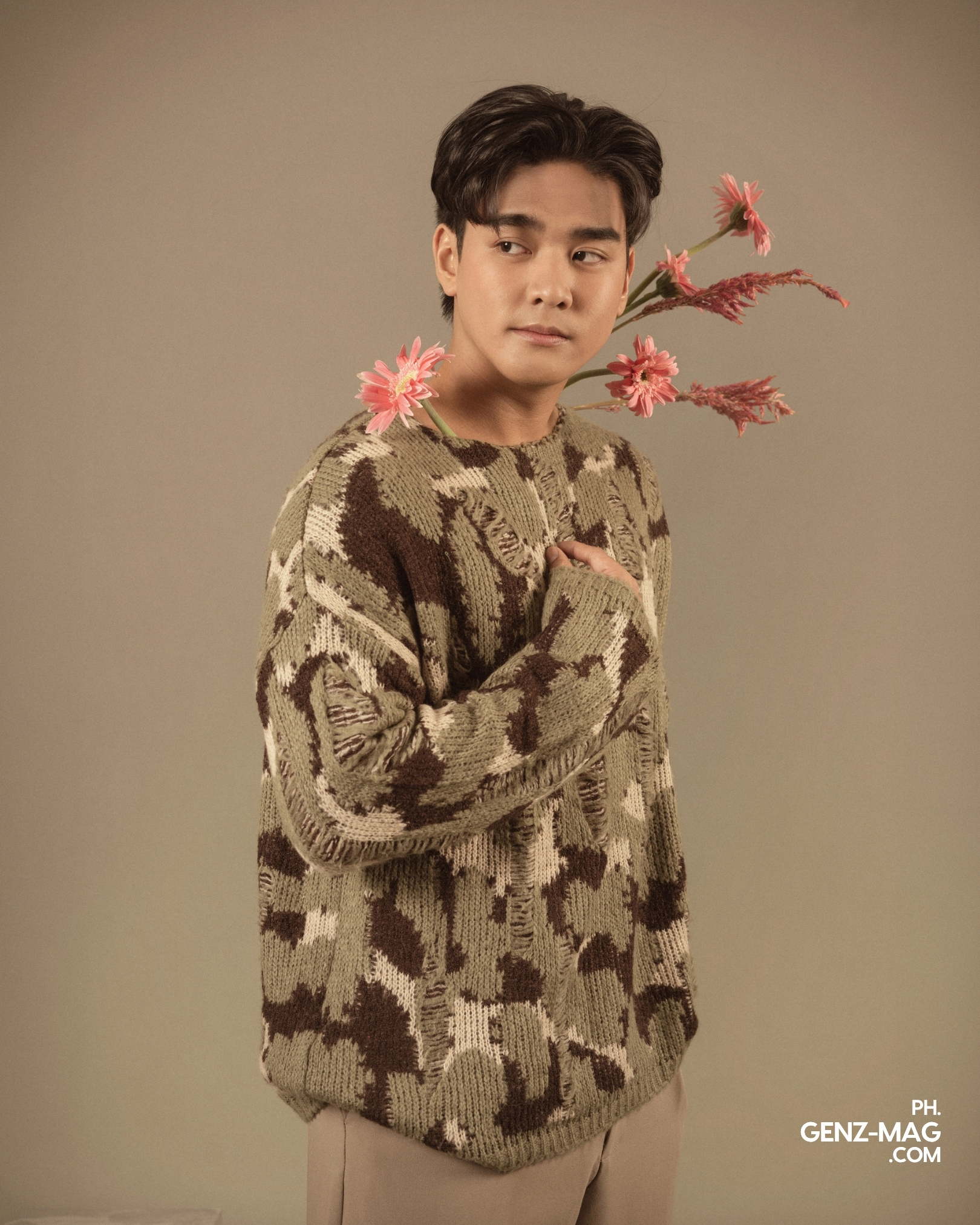 Michael Sager glancing sideways in a knit sweater, pink gerbera daisies and astilbe framing his shoulder, floral styling by Makati Flower Atelier, for GEN Z Magazine's cover story with Zephanie