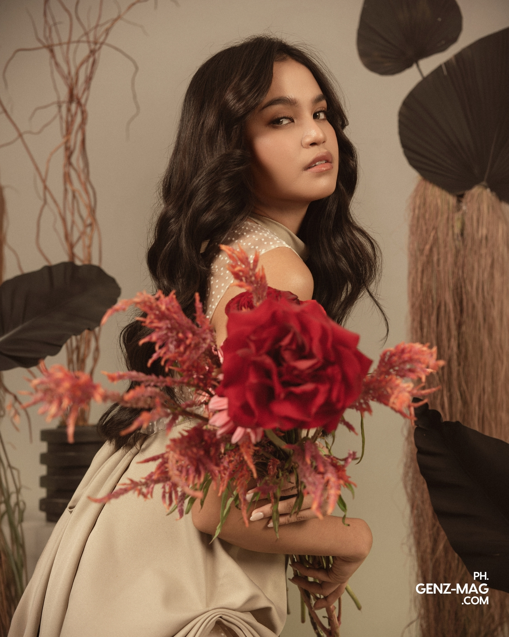 Zephanie glancing over her shoulder in a polka-dot and draped beige dress, holding a bouquet of red roses and astilbe, with floral styling by Makati Flower Atelier, shot at The Villa Studios, for GEN Z Magazine's cover story with Michael Sager