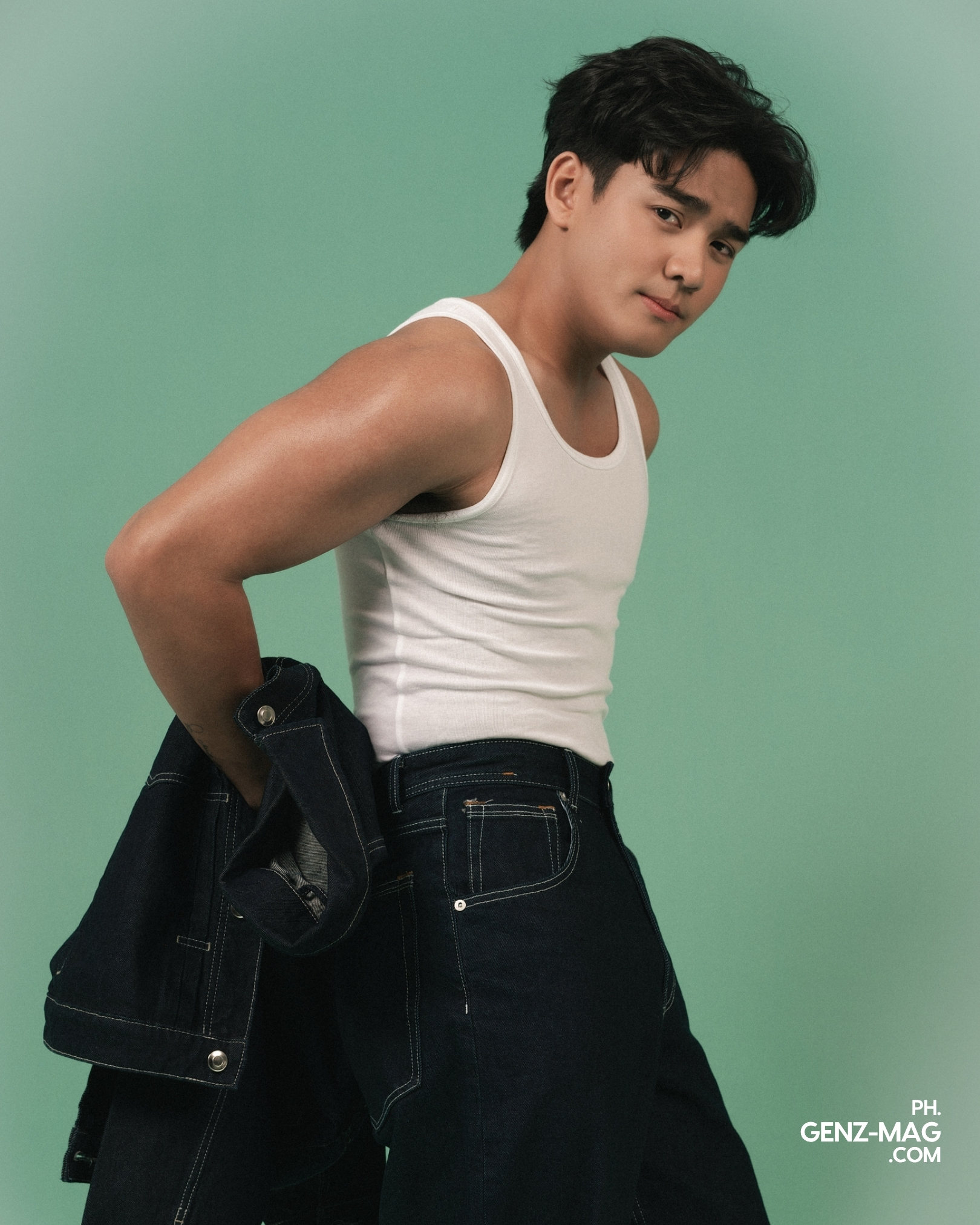 Michael Sager looking over his shoulder in a white tank top and dark denim, jacket draped over his arm, for GEN Z Magazine's cover story with Zephanie.