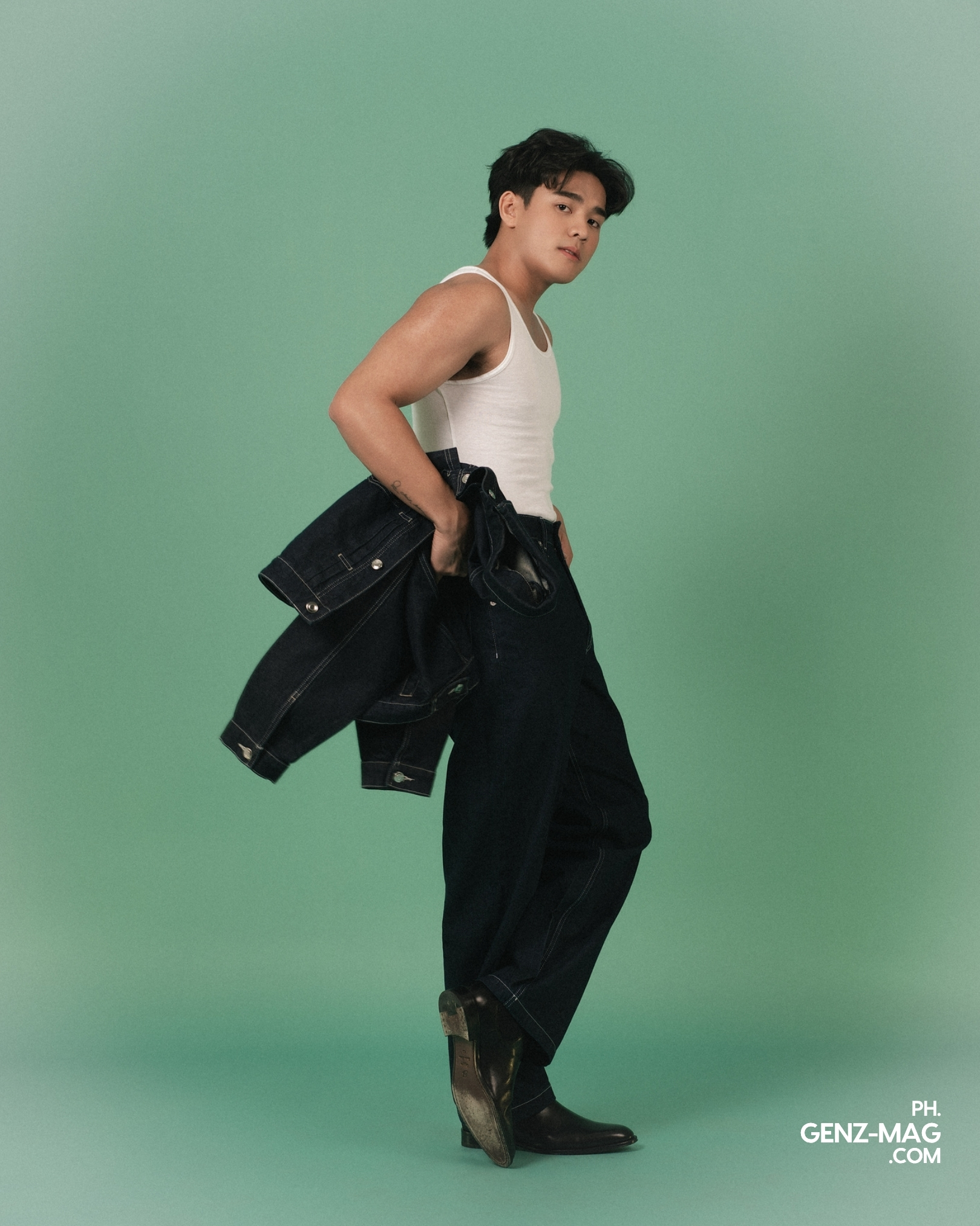 Michael Sager mid-stride in a white tank top and wide-leg dark denim, carrying a matching jacket, for GEN Z Magazine's cover story with Zephanie.