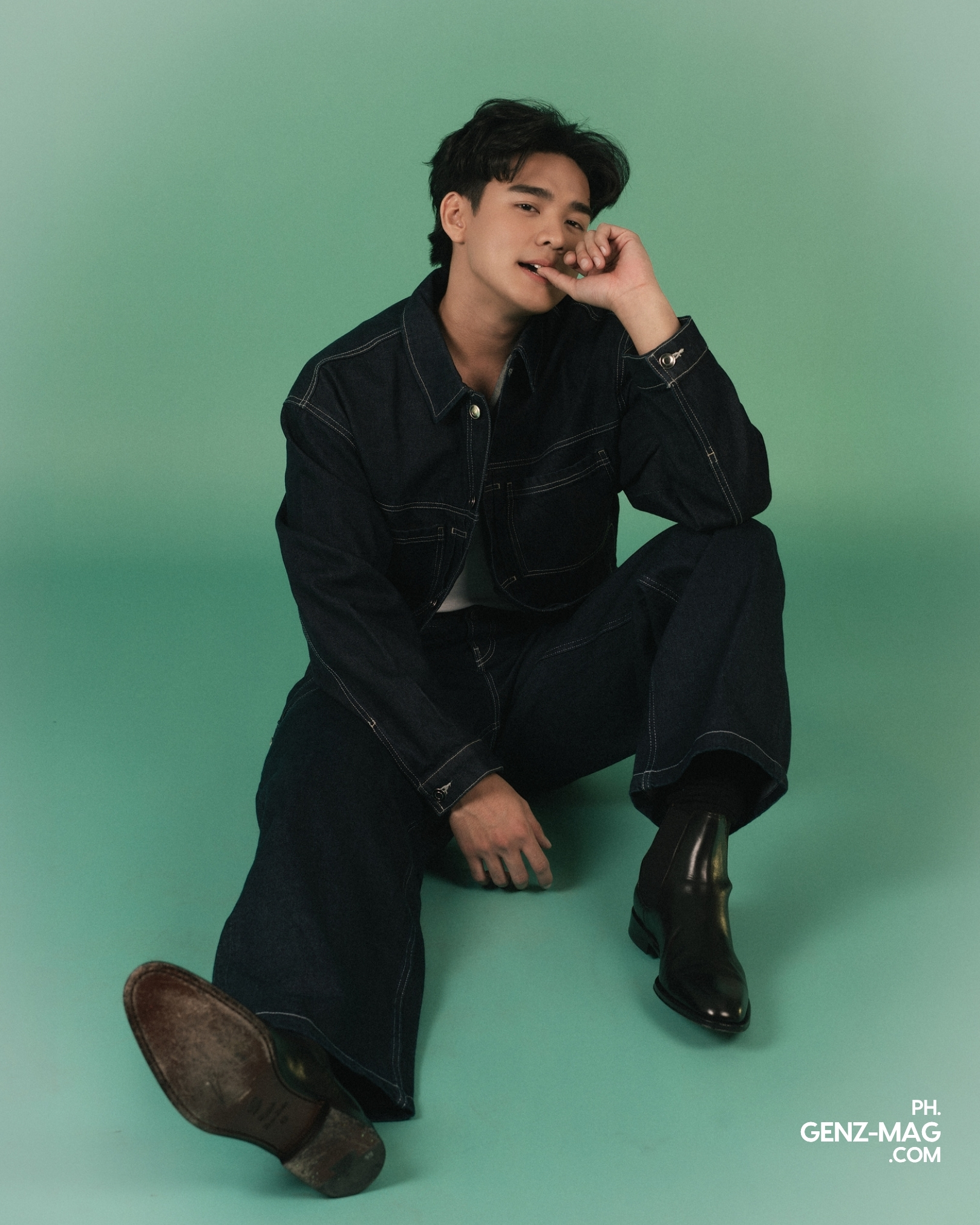 Michael Sager seated on the floor in a cropped denim jacket and wide-leg jeans, chin resting on his hand, for GEN Z Magazine's cover story with Zephanie.