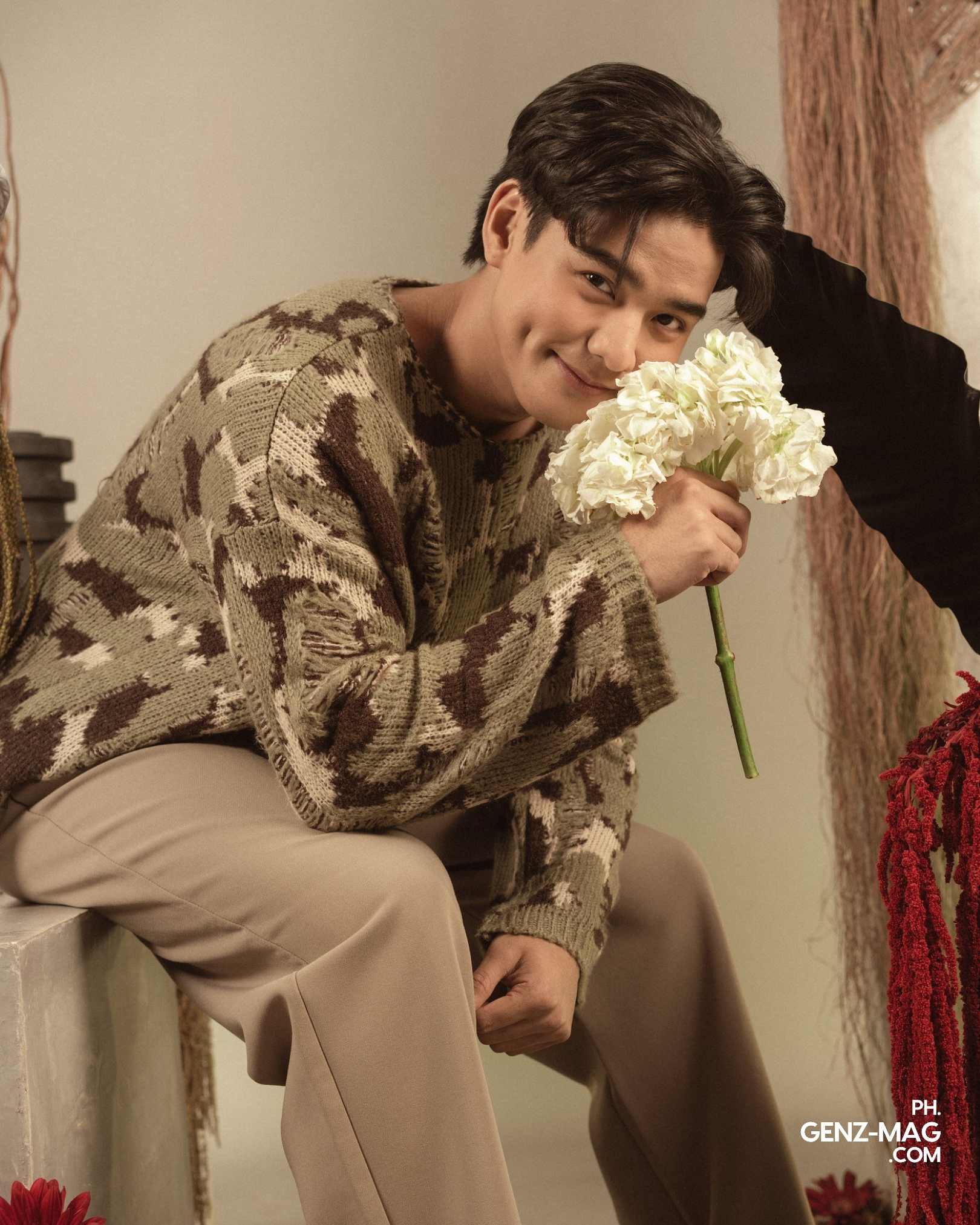 Michael Sager perched on a pedestal, smiling while holding white hydrangeas up to his cheek, with floral styling by Makati Flower Atelier, for GEN Z Magazine's cover story with Zephanie