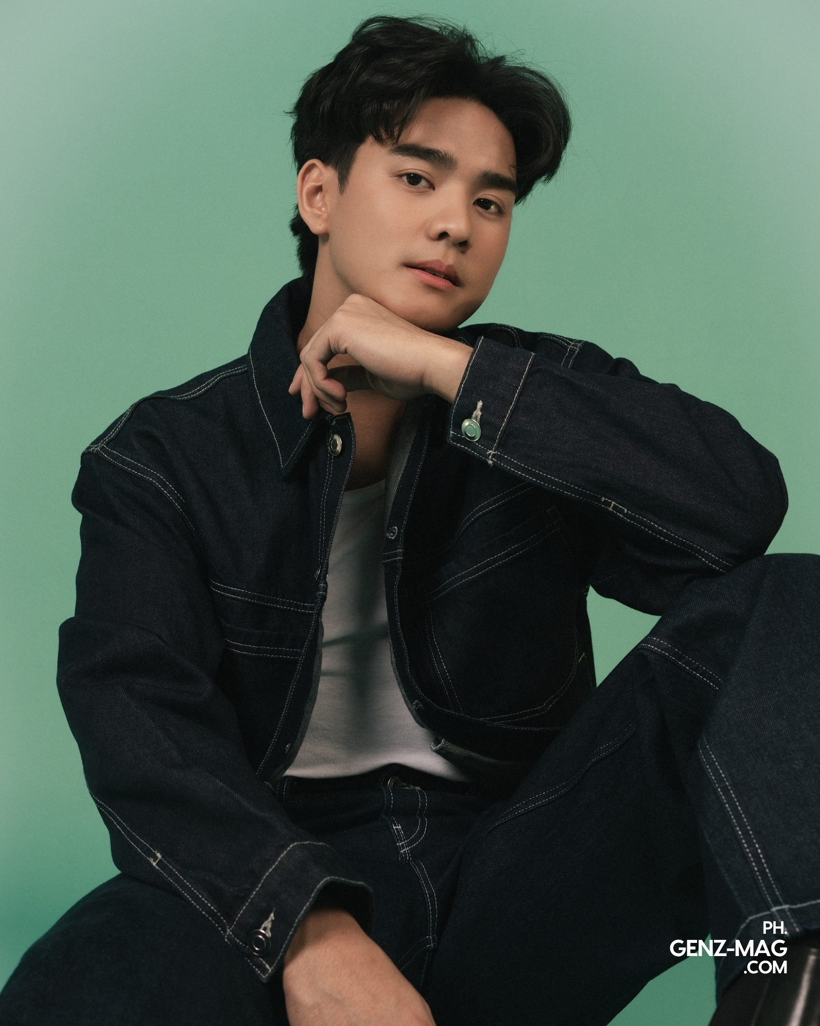 Michael Sager seated on the floor in a cropped denim jacket and wide-leg jeans, chin resting on his hand, for GEN Z Magazine's cover story with Zephanie